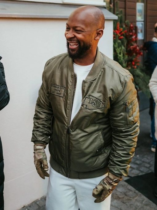 Man wearing a green bomber jacket with patches, standing outdoors in France Style